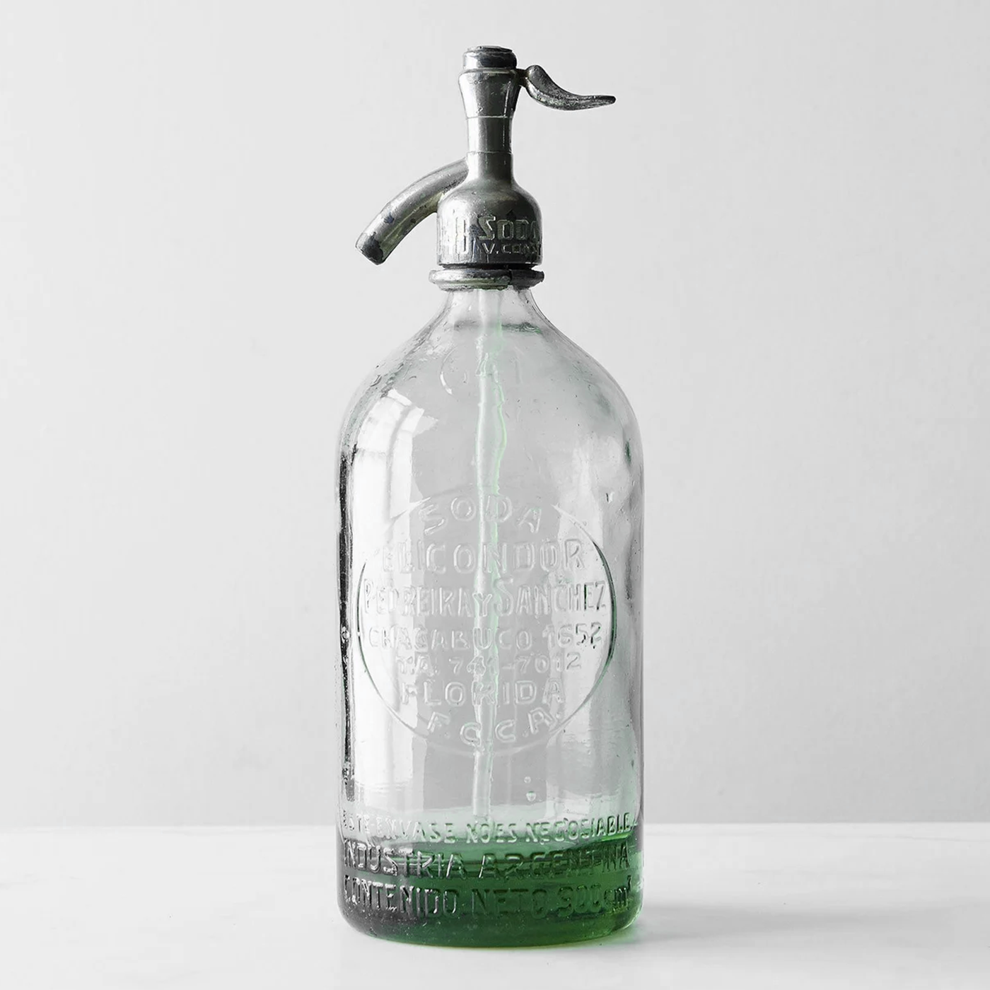 Clear vintage Argentine seltzer bottle with every embossed detail of the soda house visible